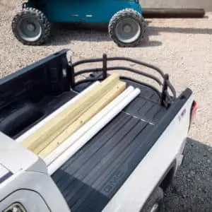 Genuine GM bed extender holding lumber upright in the box of a white GMC truck