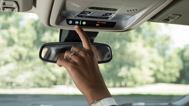 Driver pressing the blue OnStar button on the overhead console of a vehicle