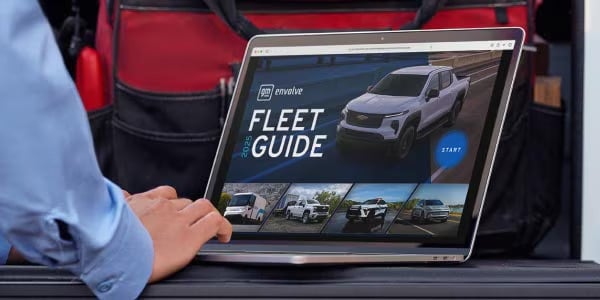 Laptop resting on a truck tailgate showing the start screen of the 2025 interactive GM Fleet Guide