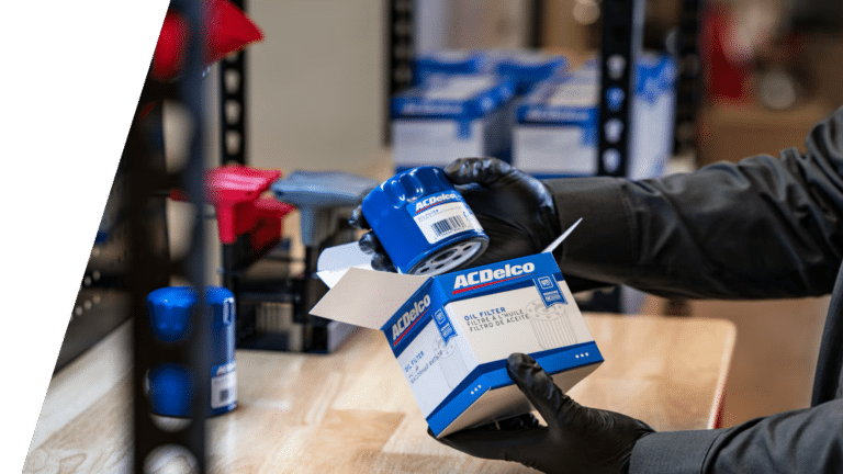 Gloved hands unboxing an ACDelco genuine GM oil filter at a parts counter