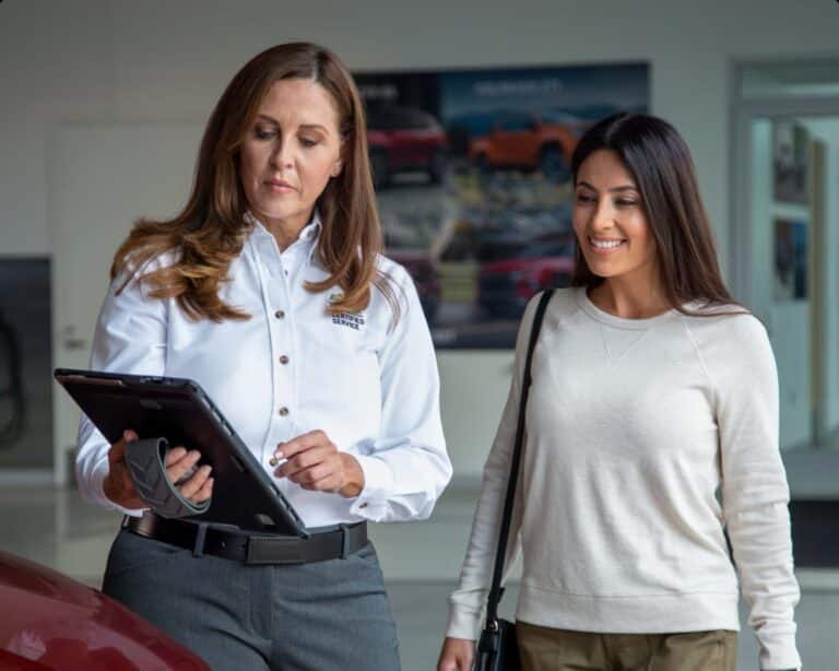 Certified Service advisor showing information on a tablet to a customer in a dealership showroom