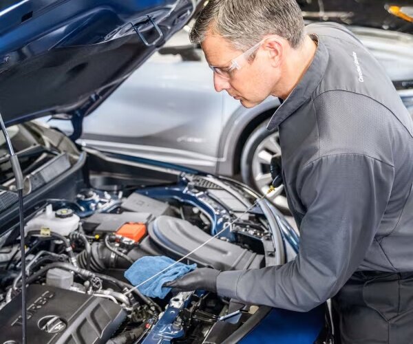 GM Certified Service technician checking fluid levels under the hood of a blue vehicle