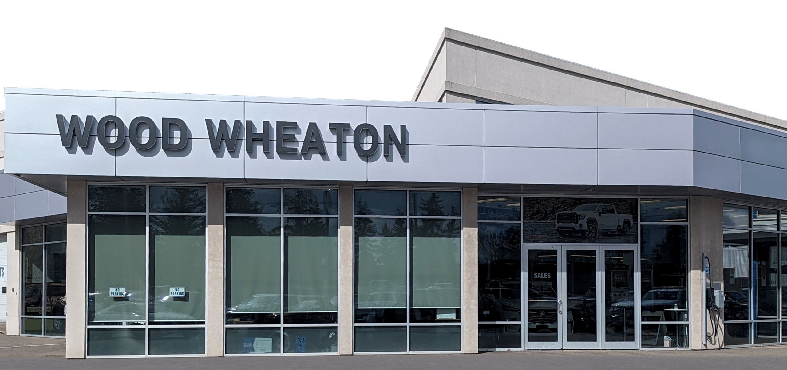 Car dealership exterior with "Wood Wheaton" signage and large windows.